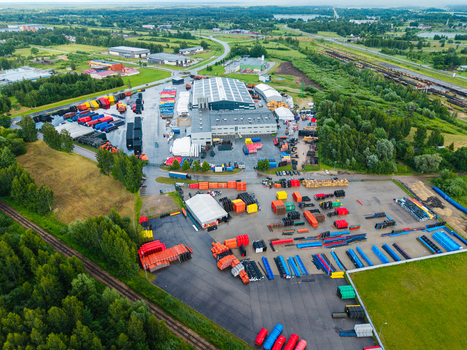 Jelgava Latvia 04 July 2026 Aerial view of a polymer pipe manufacturing facility featuring industrial buildings outdoor storage areas with colorful pipes and surrounding green landscape.