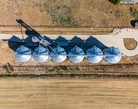 Aerial view of grain silos and metal storage tanks at an agricultural facility in Paszto Nograd County Hungary surrounded by summer farmland and rural countryside. Aerial view of grain silos and metal storage tanks at an agricultural facility in Paszto Nograd County Hungary surrounded by summer farmland and rural countryside.