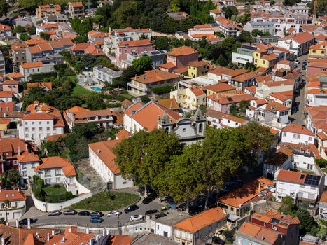Aerial view of Igreja de Sao Joao Baptista da Foz do Douro surrounded by historic residential buildings terracotta rooftops and lush trees in Porto Porto Portugal.