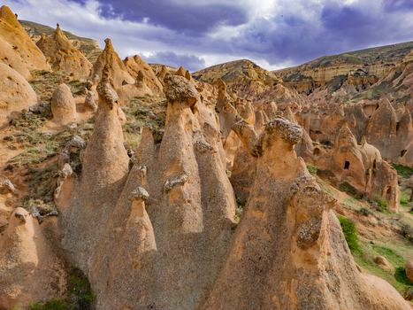 Aerial view of the unique fairy chimneys and rock formations in Zelve Vadisi with rugged terrain and dramatic cloudy sky in Goreme Nevsehir Turkiye. Aerial view of the unique fairy chimneys and rock formations in Zelve Vadisi with rugged terrain and dramatic cloudy sky in Goreme Nevsehir Turkiye.