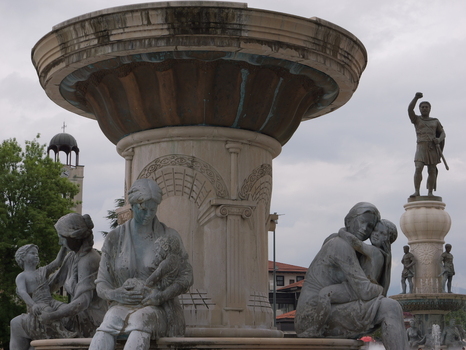 View of the Fountain Olympia featuring bronze sculptures of women and children with the Warrior on a Horse monument in the background in Skopje Greater Skopje North Macedonia. View of the Fountain Olympia featuring bronze sculptures of women and children with the Warrior on a Horse monument in the background in Skopje Greater Skopje North Macedonia.
