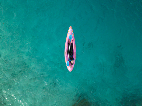 Aerial view of a person on a pink paddleboard drifts silently on the turquoise water Menjangan Kecil Island Karimunjawa Jawa Tengah Indonesia.