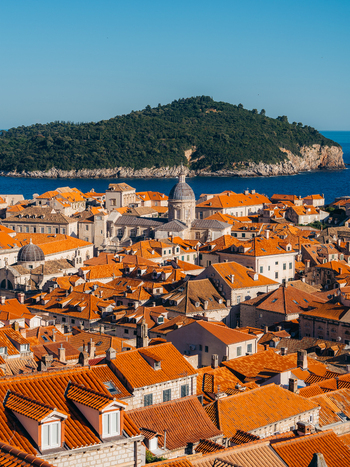 View of the historic orange tiled rooftops and the Cathedral of the Assumption dome in the Old Town with Lokrum Island in the distance Dubrovnik Dubrovnik Neretva County Croatia. View of the historic orange tiled rooftops and the Cathedral of the Assumption dome in the Old Town with Lokrum Island in the distance Dubrovnik Dubrovnik Neretva County Croatia.