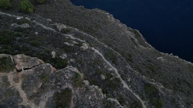 Aerial view of coastal cliffs and hiking path in Spain.
