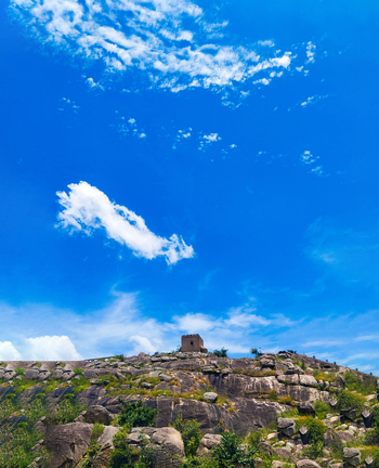 View of a stone structure atop a rocky hill under a bright blue sky in Jos North Plateau Nigeria.