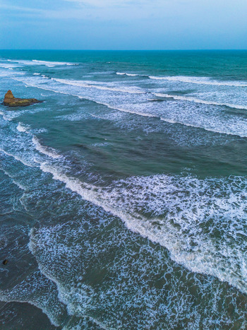 Aerial view of ocean waves crashing against a rocky outcrop along the coastline in Bali Bali Indonesia. Aerial view of ocean waves crashing against a rocky outcrop along the coastline in Bali Bali Indonesia.