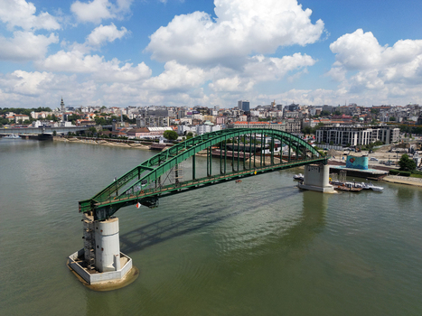 Aerial view of Savski most a green arched bridge spanning the Sava River with the urban skyline and modern buildings in the background under a blue sky. Belgrade City of Belgrade Serbia. Aerial view of Savski most a green arched bridge spanning the Sava River with the urban skyline and modern buildings in the background under a blue sky. Belgrade City of Belgrade Serbia.