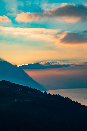 Aerial view of the Swiss Alps at sunset with dramatic clouds over the mountains and a lake below in Airolo Ticino Switzerland. Aerial view of the Swiss Alps at sunset with dramatic clouds over the mountains and a lake below in Airolo Ticino Switzerland.