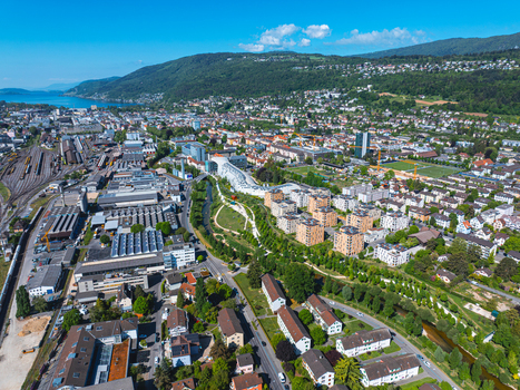 Aerial view of the modern Swatch headquarters and industrial zones surrounded by residential blocks and green parks in Biel Bienne Canton of Bern Switzerland.