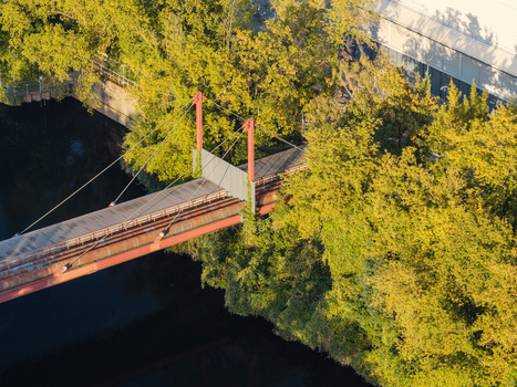 Aerial view of the pipeline bridge at the Combined Heat and Power Plant Lichterfelde featuring red support structures and lush green trees along the canal in Berlin Berlin Germany. Aerial view of the pipeline bridge at the Combined Heat and Power Plant Lichterfelde featuring red support structures and lush green trees along the canal in Berlin Berlin Germany.