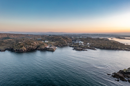Aerial view of the rugged coastline and small pier at Kincasslagh during golden hour with rocky terrain and calm waters in Kincasslagh County Donegal Ireland. Aerial view of the rugged coastline and small pier at Kincasslagh during golden hour with rocky terrain and calm waters in Kincasslagh County Donegal Ireland.