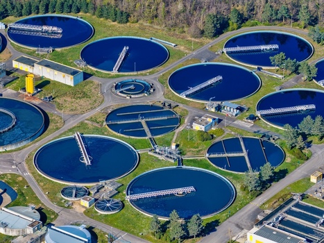 Aerial view of a complex of circular water treatment pools reflecting the sky surrounded by greenery and industrial buildings Sausheim Grand Est France.