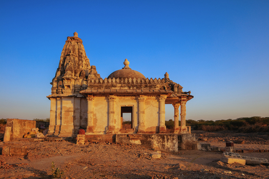 View of the historic Verawah Temple with intricate stone carvings under a clear blue sky in the desert landscape of Nagarparkar Sindh Pakistan.