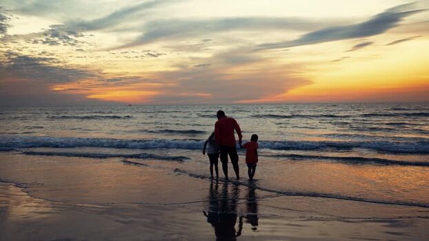 View of a father and children on the beach at sunset Bangladesh.