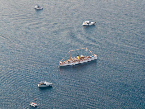 Aerial view of a classic yacht with a yellow funnel sailing among modern luxury motor yachts in the blue Mediterranean Sea near Cannes Provence Alpes Cote d Azur France. Aerial view of a classic yacht with a yellow funnel sailing among modern luxury motor yachts in the blue Mediterranean Sea near Cannes Provence Alpes Cote d Azur France.