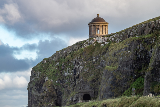 View of the historic Mussenden Temple perched on the dramatic cliff edge overlooking the coast in Downhill Northern Ireland United Kingdom. View of the historic Mussenden Temple perched on the dramatic cliff edge overlooking the coast in Downhill Northern Ireland United Kingdom.