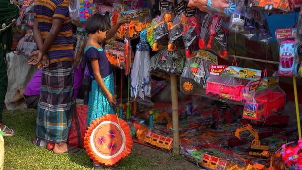View of a girl looking at toys at a market stall in Bangladesh. View of a girl looking at toys at a market stall in Bangladesh.