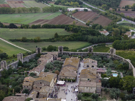 Aerial view of the historic walled town of Monteriggioni featuring stone fortifications medieval buildings and surrounding olive groves in the Tuscan countryside Monteriggioni Tuscany Italy.