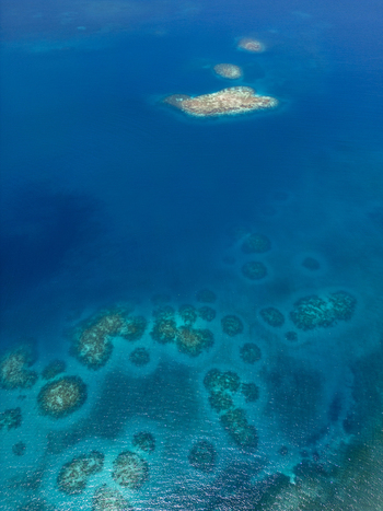 Aerial view of coral reefs and small tropical islands surrounded by turquoise and deep blue Caribbean waters Guanaja Bay Islands Department Honduras. Aerial view of coral reefs and small tropical islands surrounded by turquoise and deep blue Caribbean waters Guanaja Bay Islands Department Honduras.