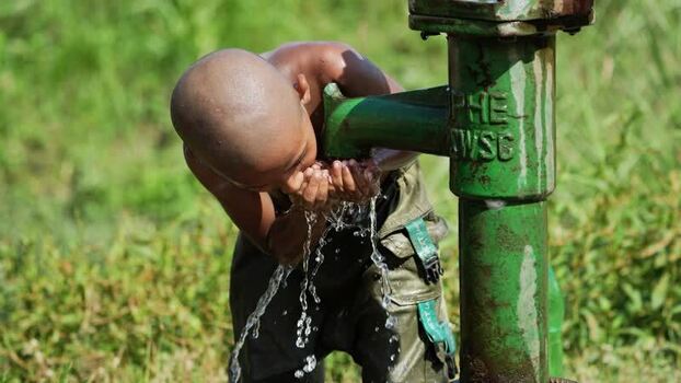 View of a boy drinking water from a hand pump Bangladesh. View of a boy drinking water from a hand pump Bangladesh.