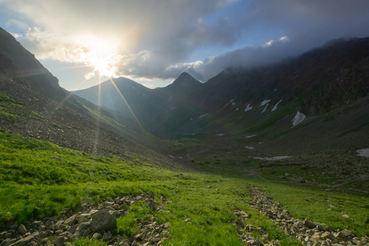 View of Smutne sedlo in Western Tatras with green grassy slopes and rocky terrain under a bright sun and cloudy sky Ziar Zilina Region Slovakia. View of Smutne sedlo in Western Tatras with green grassy slopes and rocky terrain under a bright sun and cloudy sky Ziar Zilina Region Slovakia.