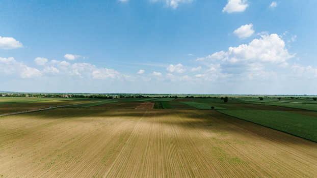 Aerial view of vast agricultural fields and patchwork farmland under a blue sky with scattered clouds in Novi Sad Vojvodina Serbia. Aerial view of vast agricultural fields and patchwork farmland under a blue sky with scattered clouds in Novi Sad Vojvodina Serbia.