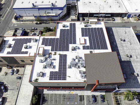 Aerial view of a commercial building roof featuring an extensive solar panel layout and HVAC units in Los Angeles California United States. Aerial view of a commercial building roof featuring an extensive solar panel layout and HVAC units in Los Angeles California United States.