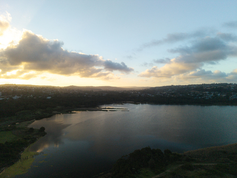 Aerial view of Dee Why Lagoon at sunset with golden light reflecting on the water surrounded by lush vegetation and urban landscape in Dee Why New South Wales Australia. Aerial view of Dee Why Lagoon at sunset with golden light reflecting on the water surrounded by lush vegetation and urban landscape in Dee Why New South Wales Australia.