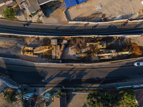 Aerial view of a construction site with heavy machinery and excavators working between two asphalt roads in Yogyakarta Special Region of Yogyakarta Indonesia. Aerial view of a construction site with heavy machinery and excavators working between two asphalt roads in Yogyakarta Special Region of Yogyakarta Indonesia.