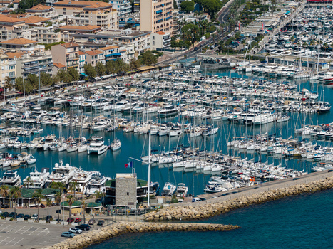 Aerial view of Port Vauban marina filled with numerous yachts and boats protected by a stone breakwater with urban buildings in the background in Antibes Provence Alpes Cote d Azur France. Aerial view of Port Vauban marina filled with numerous yachts and boats protected by a stone breakwater with urban buildings in the background in Antibes Provence Alpes Cote d Azur France.