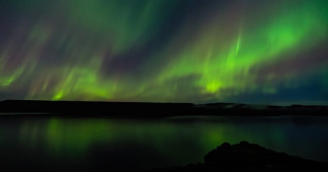 View of the aurora borealis over water Iceland.