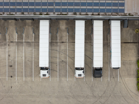 Aerial view of semi trucks parked at a modern distribution center loading dock with solar panels installed on the warehouse roof in Genk Flanders Belgium. Aerial view of semi trucks parked at a modern distribution center loading dock with solar panels installed on the warehouse roof in Genk Flanders Belgium.