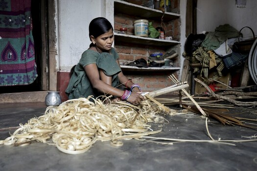 Odisha India 26 March 2026 View of a woman skillfully crafting bamboo strips inside a rustic dwelling surrounded by scattered fragments under soft light. Odisha India 26 March 2026 View of a woman skillfully crafting bamboo strips inside a rustic dwelling surrounded by scattered fragments under soft light.
