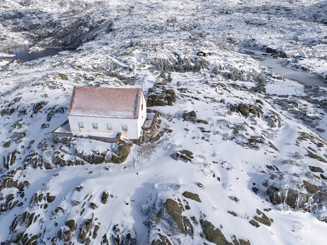Aerial view of a white building with a red roof standing out against the snow covered rocky landscape Lagoa Comprida São Romão Serra da Estrella Portugal. Aerial view of a white building with a red roof standing out against the snow covered rocky landscape Lagoa Comprida São Romão Serra da Estrella Portugal.