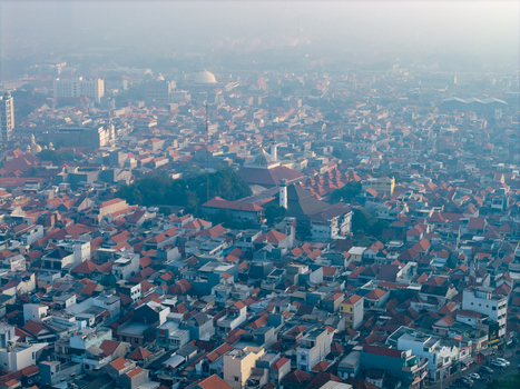 Genteng East Java Indonesia 13 August 2026 Aerial view of Surabaya Old Town with dense historic rooftops narrow streets and traditional mosque architecture under a hazy sky. Genteng East Java Indonesia 13 August 2026 Aerial view of Surabaya Old Town with dense historic rooftops narrow streets and traditional mosque architecture under a hazy sky.