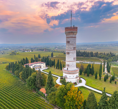 Aerial view of the Tower of San Martino della Battaglia surrounded by lush vineyards and cypress trees under a soft sunset sky in San Martino della Battaglia Lombardia Italy. Aerial view of the Tower of San Martino della Battaglia surrounded by lush vineyards and cypress trees under a soft sunset sky in San Martino della Battaglia Lombardia Italy.