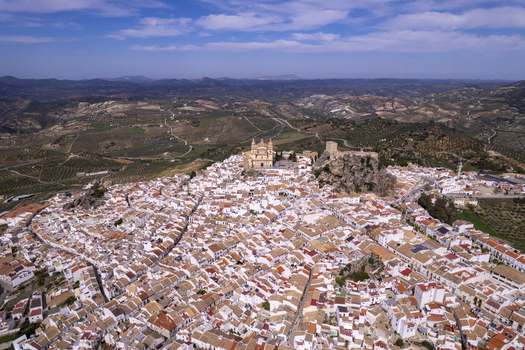 Aerial view of the historic white village of Olvera with its hilltop church and castle surrounded by rolling hills and olive groves in Olvera Andalusia Spain. Aerial view of the historic white village of Olvera with its hilltop church and castle surrounded by rolling hills and olive groves in Olvera Andalusia Spain.