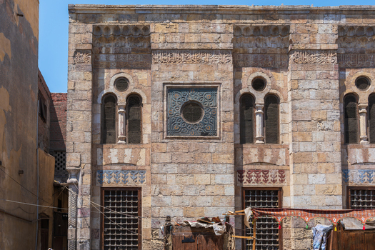 View of the intricate stone facade of the Mosque and Khanqah of Al Nasir Faraj Ibn Barquq with arched windows and decorative carvings El Gamaleya Cairo Governorate Egypt. View of the intricate stone facade of the Mosque and Khanqah of Al Nasir Faraj Ibn Barquq with arched windows and decorative carvings El Gamaleya Cairo Governorate Egypt.