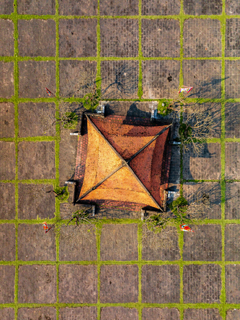Aerial view of a traditional tiled roof structure centered within a geometric grid of stone pavers and grass in Vietnam. Aerial view of a traditional tiled roof structure centered within a geometric grid of stone pavers and grass in Vietnam.