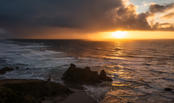 Aerial view of sea stacks along the rugged coastline during a dramatic sunset with storm clouds over the Pacific Ocean in Bandon Oregon United States. Aerial view of sea stacks along the rugged coastline during a dramatic sunset with storm clouds over the Pacific Ocean in Bandon Oregon United States.