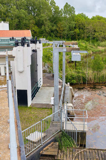 Wieringerwerf Netherlands 17 May 2026 View of Gemaal Leemans pumping station with its mechanical sluice gates white building with orange roof and lush green trees.