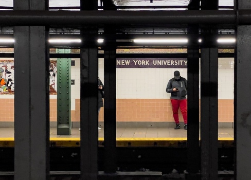 New York USA 14 May 2026 View of the New York University subway station platform with a person in red pants standing near the tiled wall and station signage. New York USA 14 May 2026 View of the New York University subway station platform with a person in red pants standing near the tiled wall and station signage.
