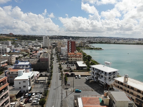 Aerial view of Arah Beach featuring a coastal promenade emerald green sea and urban buildings under a cloudy sky in Chatan Okinawa Japan. Aerial view of Arah Beach featuring a coastal promenade emerald green sea and urban buildings under a cloudy sky in Chatan Okinawa Japan.