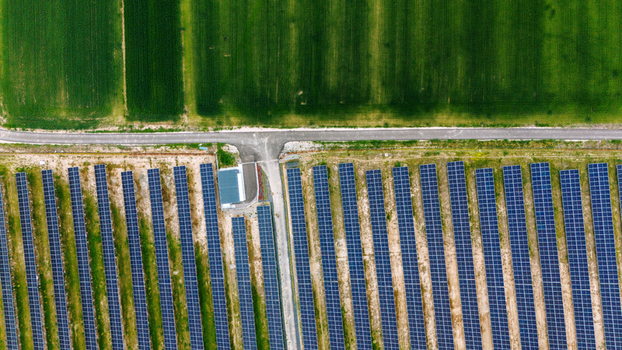 Aerial view of rows of solar panels in a photovoltaic power station next to a green agricultural field and a rural road Sabac Vojvodina Serbia.