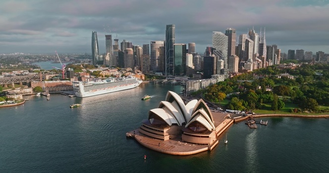 Aerial view of the iconic Sydney Opera House with its white sails set against the backdrop of the modern city skyline Sydney Harbour and a cruise ship in Sydney New South Wales Australia. Aerial view of the iconic Sydney Opera House with its white sails set against the backdrop of the modern city skyline Sydney Harbour and a cruise ship in Sydney New South Wales Australia.