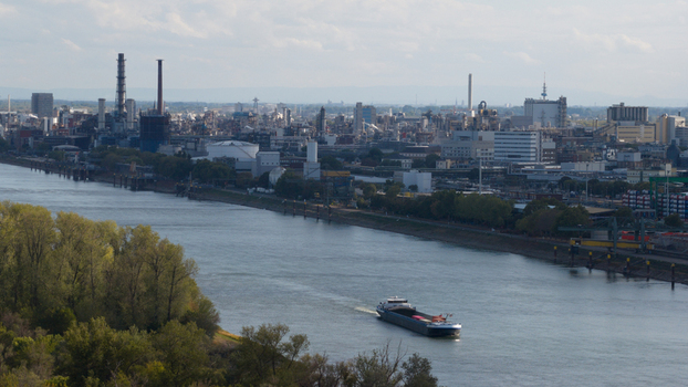Aerial view of the BASF chemical plant complex along the Rhine river with a cargo ship navigating the waterway in Ludwigshafen am Rhein Rheinland Pfalz Germany.