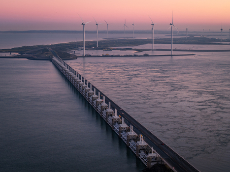 Aerial view of the Oosterscheldekering storm surge barrier and wind turbines at sunset Netherlands.
