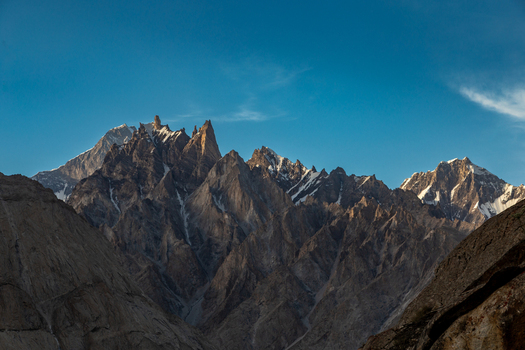 View of the jagged snow dusted peaks of the Baltoro Glacier rising against a clear blue sky in the Karakoram range Baltoro Gilgit Baltistan Pakistan.