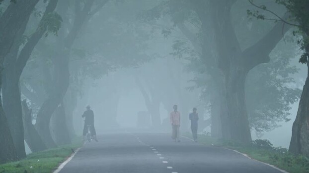 View of people walking on a foggy road in Bogura Bangladesh.