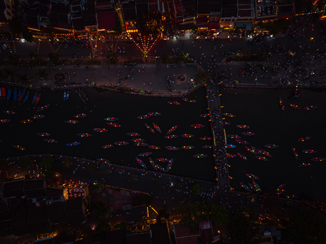 Aerial view of small boats with glowing lanterns floating on the Hoai River at night illuminated by street lights and traditional lanterns along the riverbanks in Hoi An Vietnam. Aerial view of small boats with glowing lanterns floating on the Hoai River at night illuminated by street lights and traditional lanterns along the riverbanks in Hoi An Vietnam.
